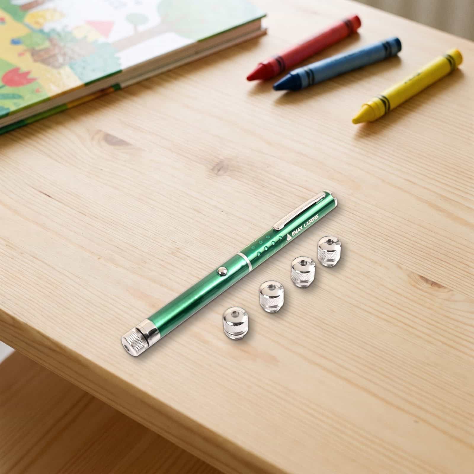 Emax green laser pointer with five caps in a real setting