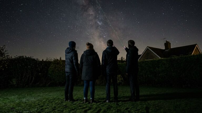 A thin green beam tracing a constellation over a British lawn